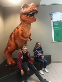 Students in front of a T-Rex statue